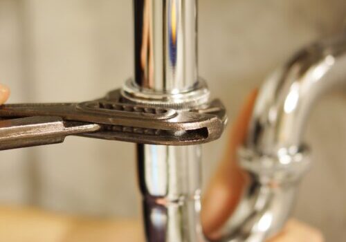 Plumbing repair service. Professional installer with spanner checking pipe.